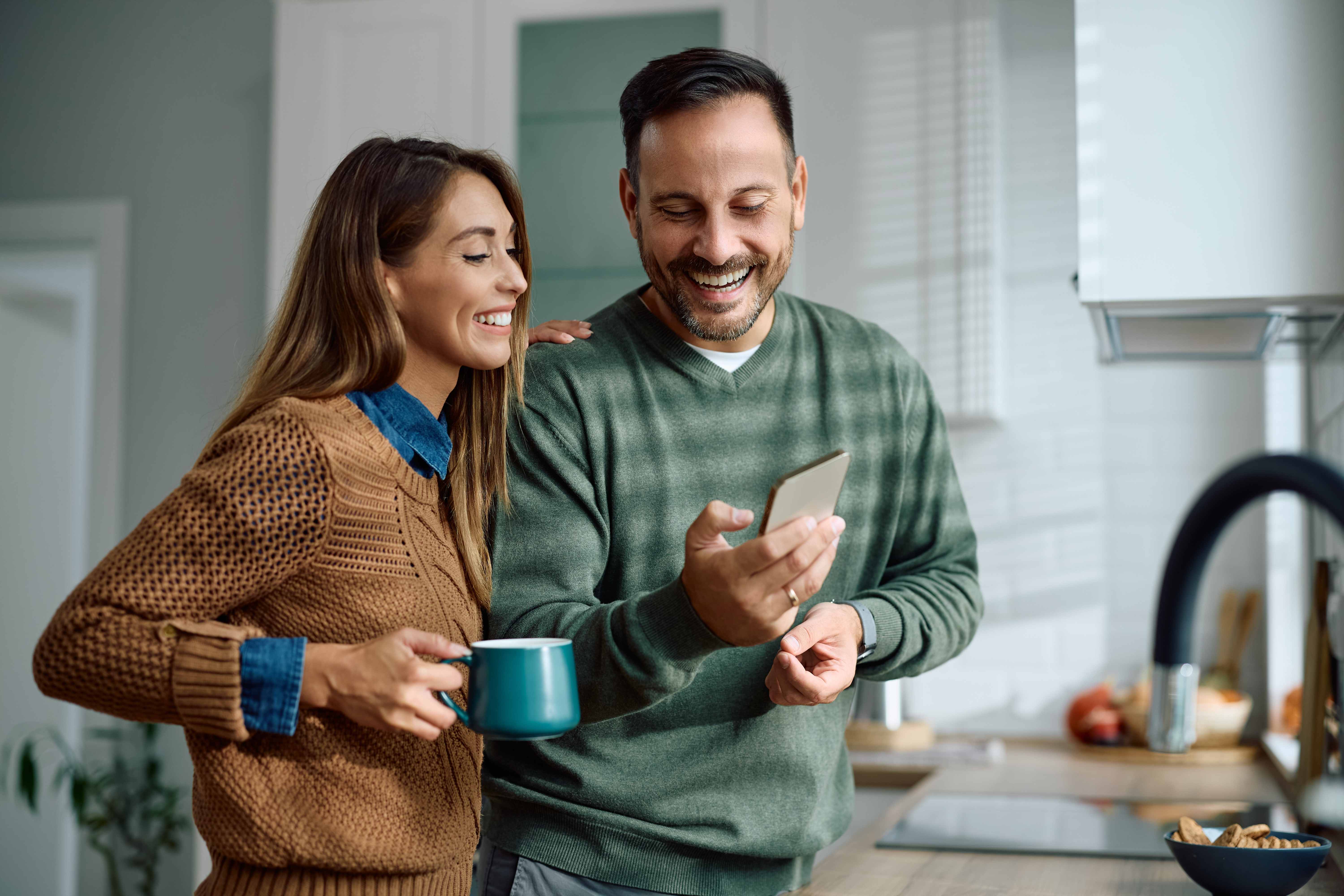 Happy couple using fasting app in kitchen